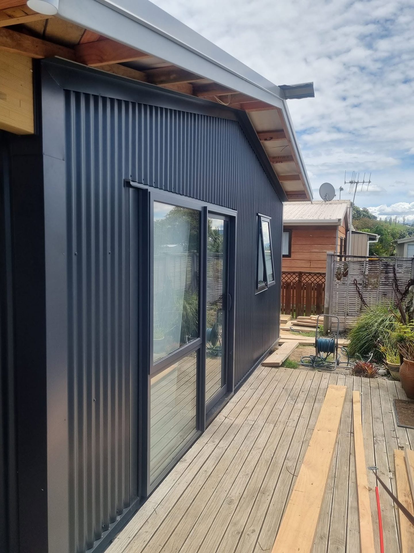 Black corrugate house exterior with a timber-framed deck